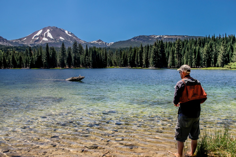 Fisherman looking at Lassen Peak on Manzanita Lake while fishing